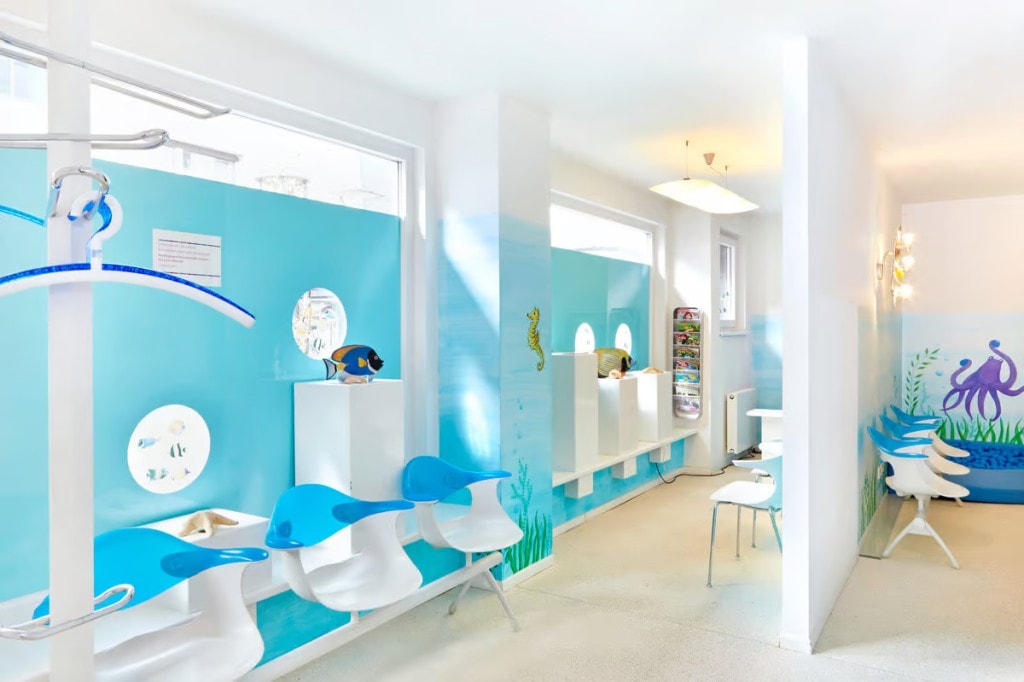 Helles, kinderfreundliches Wartezimmer der Kieferorthopädie Dr. Simone Beer, gestaltet in einem blauen Unterwasser-Thema mit Fischen und modernen Sitzen.